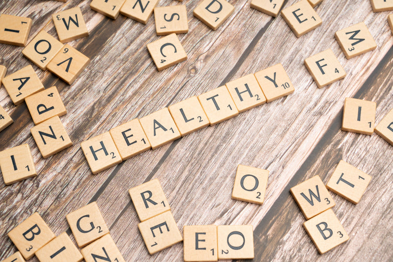 Scrabble tiles spelling out 'HEALTHY' on a wooden surface
